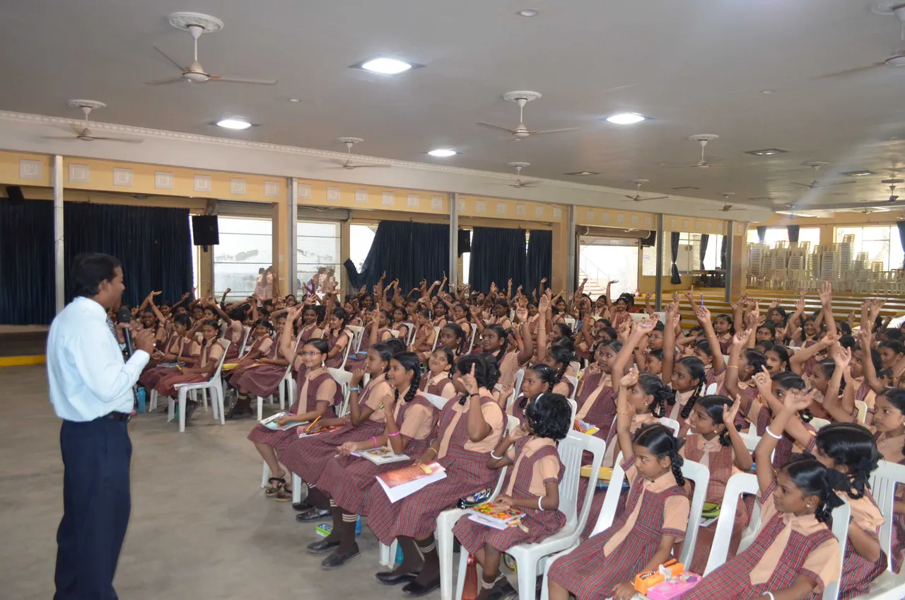 Speaker addressing attendees seated in a decorated community hall