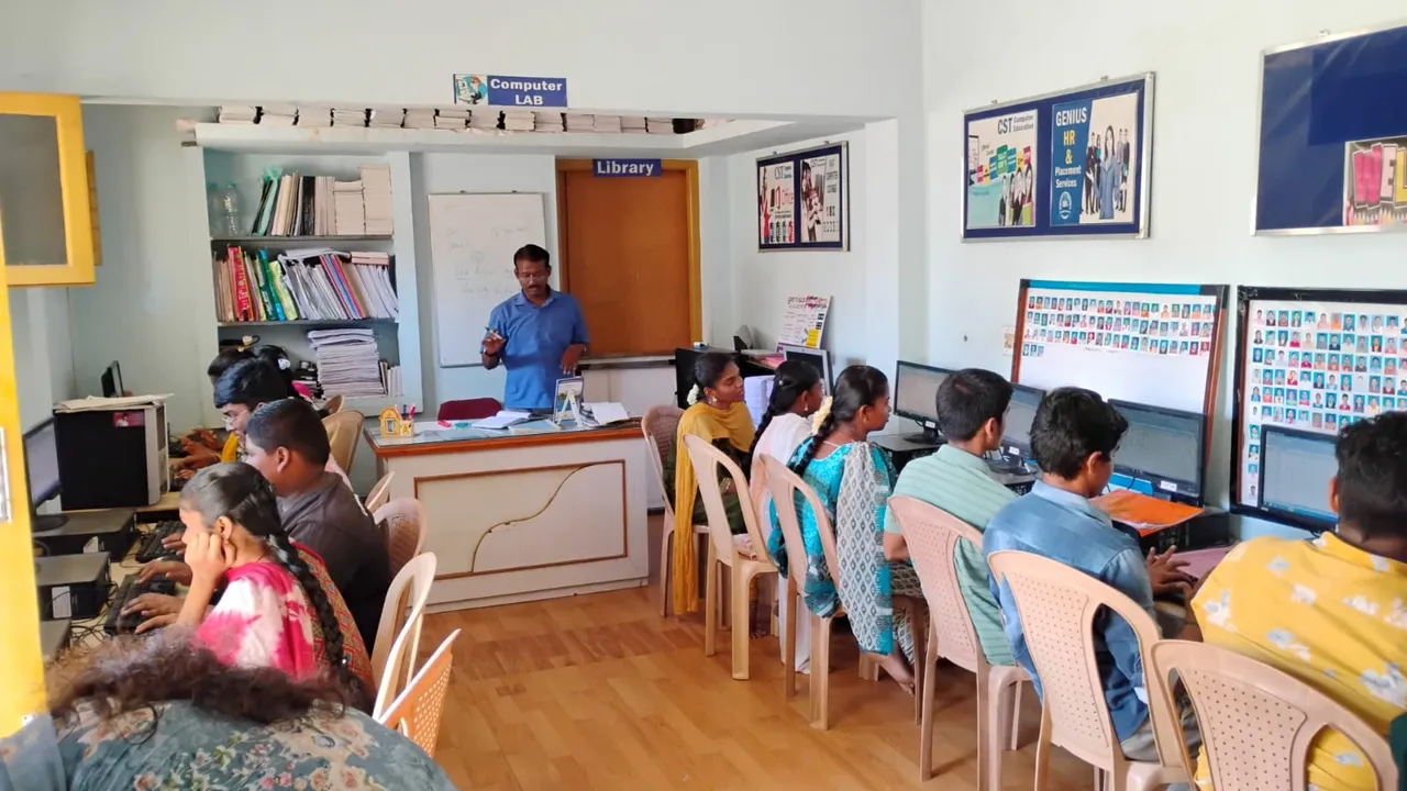 Trainer instructing learners seated at computers in a training lab