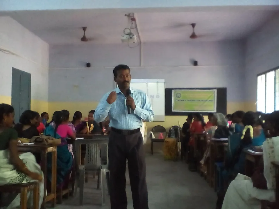 Speaker presenting beside a projector screen in a classroom