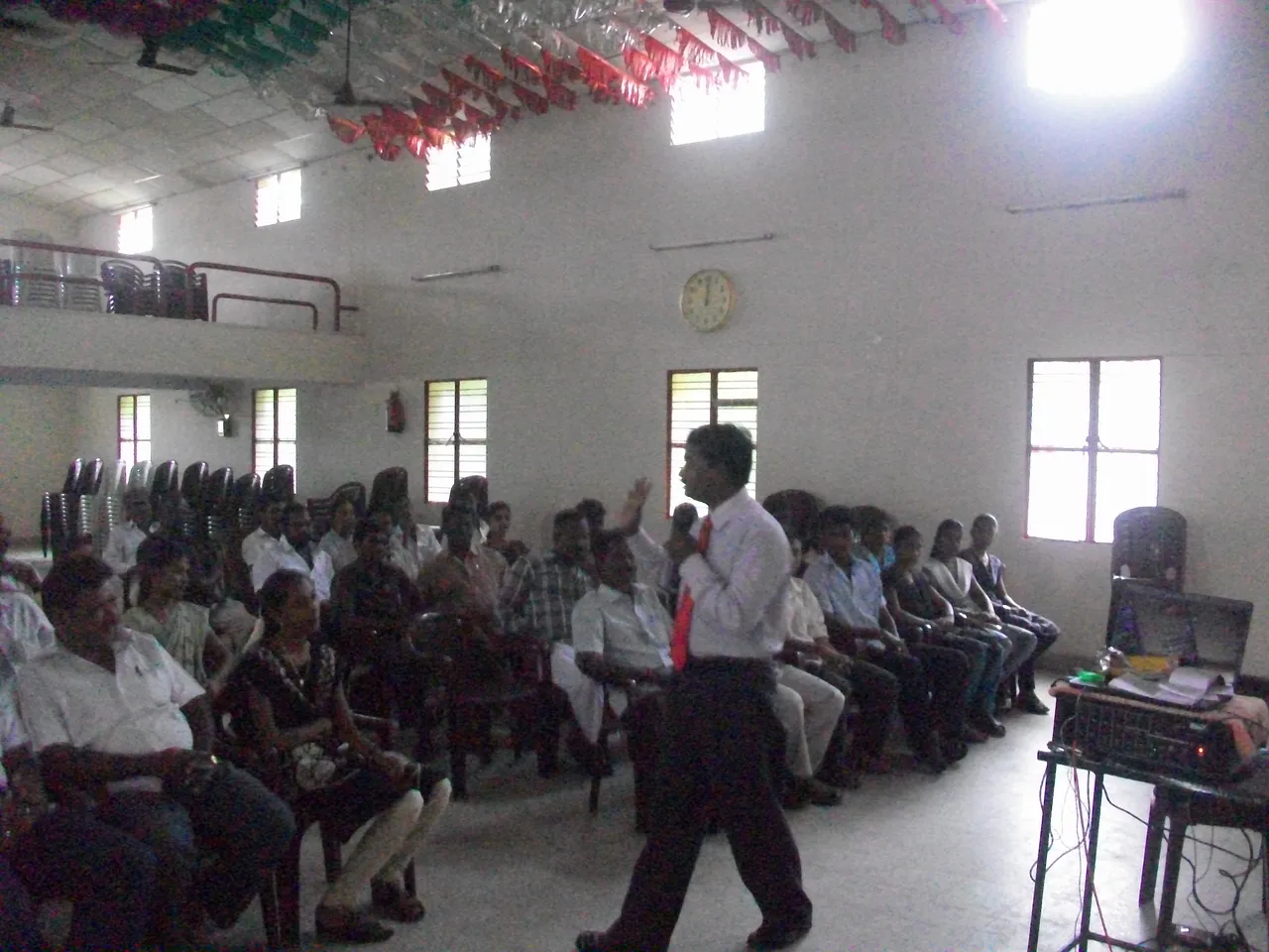 School students seated closely together across a large assembly hall
